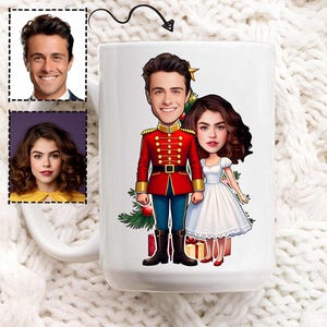 May include: White ceramic mug featuring a cartoon illustration of a man in a red military-style jacket and a woman in a white dress. The design includes a Christmas tree, gifts, and a gold star.
