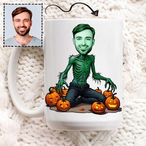 Può includere: Tazza in ceramica bianca con un'illustrazione di un uomo zombie in tonalità verdi e zucche di Halloween. Include anche un piccolo ritratto di un uomo. Design a tema Halloween.