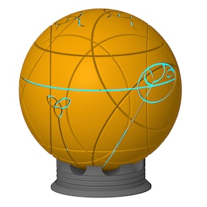 Op de afbeelding: Een gouden bol met ingewikkelde geometrische patronen en een turquoiseblauw ontwerp op een grijze basis.