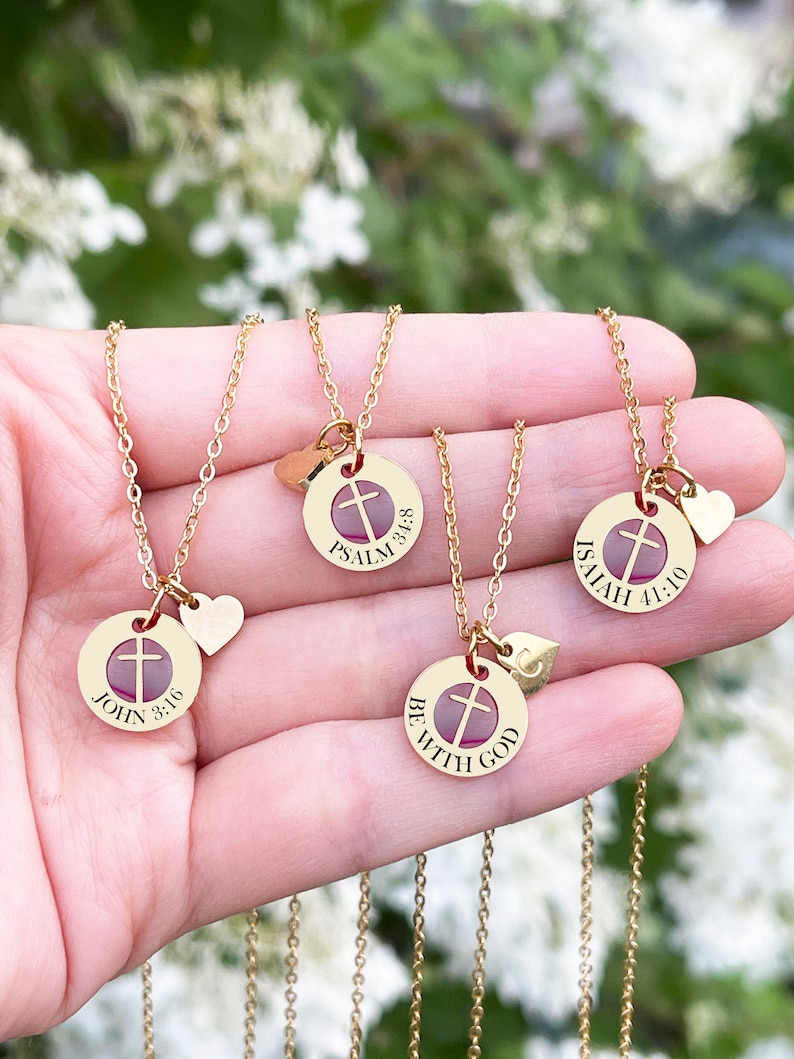 Op de afbeelding: Vier gouden kettingen met kruis hangers en kleine hartcharms. Elke hanger heeft een ander bijbelvers: Johannes 3:16, Psalm 3:5-8, Jesaja 41:10 en Wees met God.