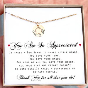 May include: A gold necklace with a pendant that says "Class of 2021" with an apple cut out in the center. The necklace is in a box with a message that reads "You are so appreciated. It takes a big heart to shape little minds. You give your time. You give your hands. But most of all you give your heart. All your time and effort doesn't go unnoticed. It makes a difference to so many people. Thank you for all that you do!"