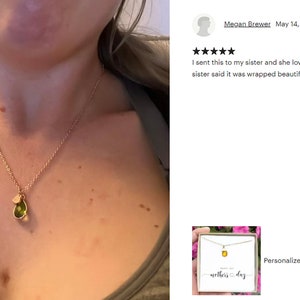 May include: Gold-toned necklace with a pendant featuring a green gemstone and a small charm. The necklace is worn on a person. The image also includes a customer review and a product image with the text "Personalize gift Happy 1st Mothers Day Gift for First..."