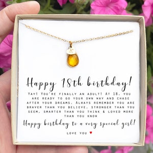 May include: A gold necklace with a small heart charm and a teardrop-shaped amber stone pendant. The necklace is in a white box with a message that reads "Happy 18th birthday! YAY! You're finally an adult! At 18, you are ready to go your own way and chase after your dreams. Always remember you are braver than you believe, stronger than you seem, smarter than you think & loved more than you know. Happy birthday to a very special girl! LOVE YOU".