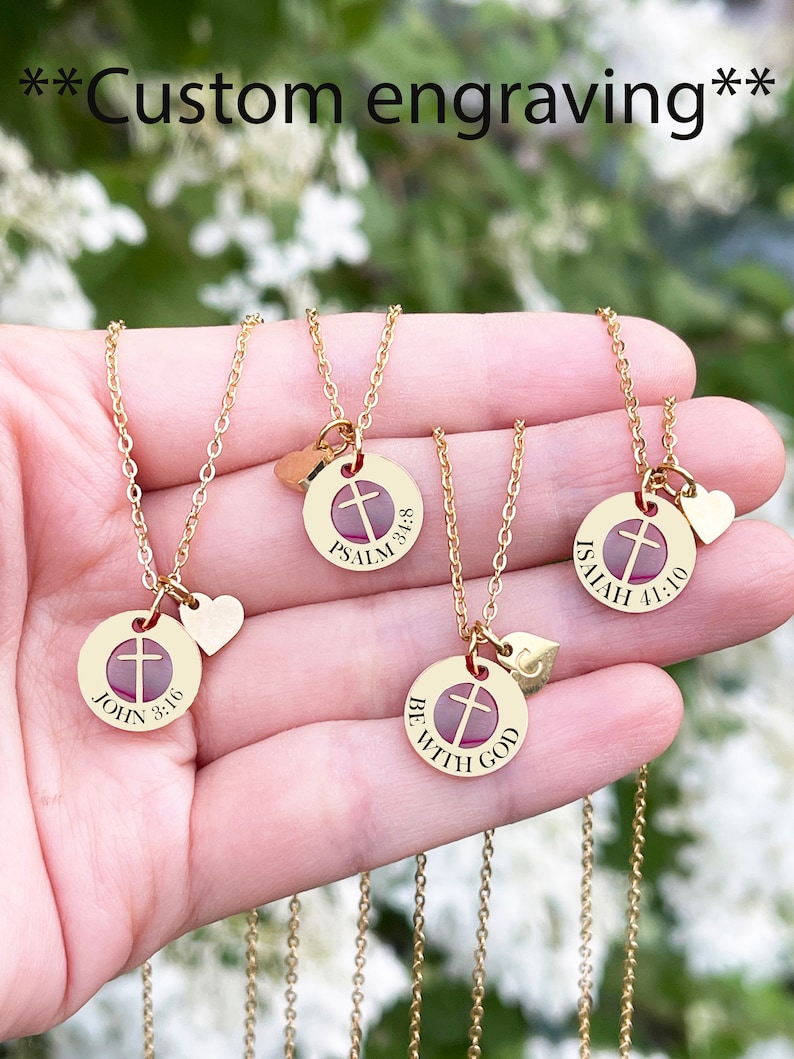Op de afbeelding: Vier gouden kettingen met kruis hangers en kleine hartjes. Elke hanger heeft een andere inscriptie: "Johannes 3:16", "Psalm 3:5-8", "Jesaja 41:10" en "Wees met God".