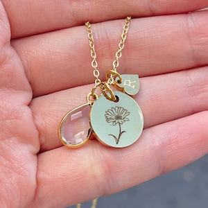 May include: Gold necklace with a flower charm, a teardrop-shaped crystal charm, and a heart charm with the letter "R" engraved on it.