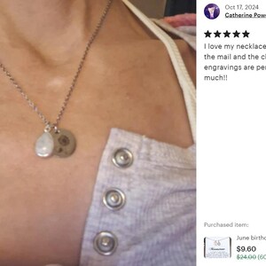 May include: A silver necklace with two charms, one round and one teardrop-shaped, hanging from it. The necklace is worn by a person with a light gray shirt. The text in the image reads: "I love my necklace! I got it super fast in the mail and the charms and the engravings are perfect!! Thank you so much!!"
