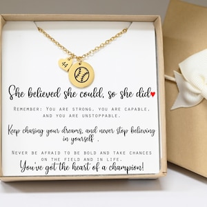 May include: A gold-colored necklace with a baseball pendant and a heart-shaped charm with the number 44. The necklace is displayed in a gift box with inspirational text. The box is inside a larger gift box with a white bow.
