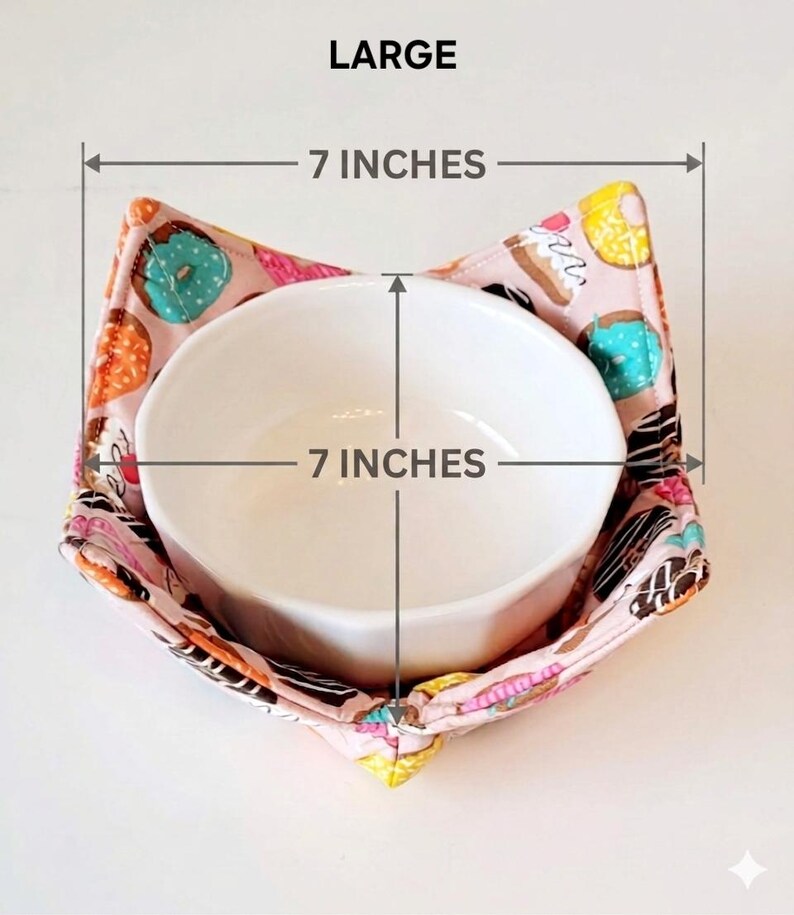 May include: A white ceramic bowl inside a pink fabric bowl cozy. The cozy is patterned with donuts in various colors. The bowl and cozy are each 7 inches in diameter. The word "LARGE" is at the top.