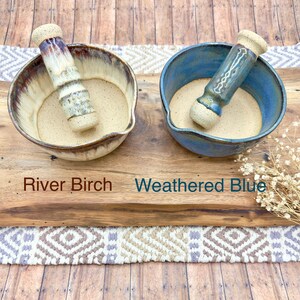 K&ouml;nnte beinhalten: Zwei M&ouml;rser- und St&ouml;&szlig;el-Sets aus Keramik. Das linke Set ist mit River Birch beschriftet und besteht aus einer cremefarbenen und braun glasierten Schale mit passendem St&ouml;&szlig;el. Das rechte Set ist mit Weathered Blue beschriftet und hat eine blaue Schale.