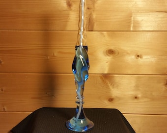 Könnte beinhalten: Ein blauer Kerzenhalter aus Glas mit einem gedrehten Design und einem weißen Docht. Die Kerze ist angezündet und die Flamme ist sichtbar.