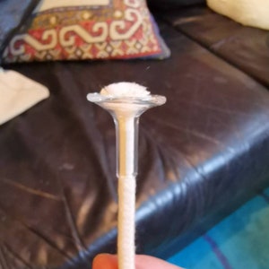Op de afbeelding: Een witte lont met een glazen bovenkant voor een kaars.
