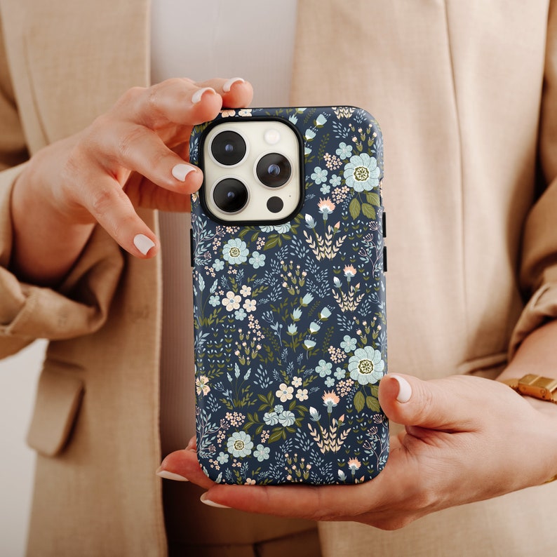 a woman holding a phone case with flowers on it