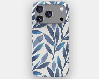 May include: A smartphone case featuring a repeating pattern of watercolor-style blue leaves on a cream-colored background. The case has a rectangular cutout at the top left for a triple-lens camera system and a flash, showing the device's back.