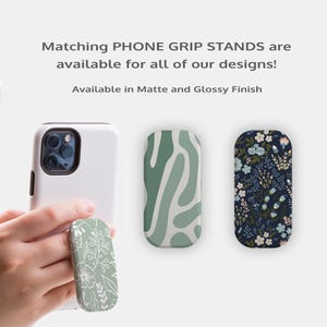 a hand holding a phone grip designed for a phone, with three different phone grip designs displayed on the phone's screen.