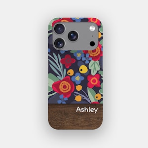 May include: A rectangular phone case featuring a dark navy blue background with a vibrant floral pattern of red, blue, and yellow flowers and green leaves. The bottom section has a dark brown wood grain texture with the white text Ashley.