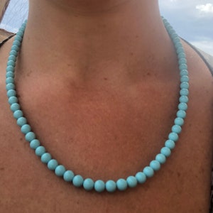 May include: A light blue beaded necklace with round beads.