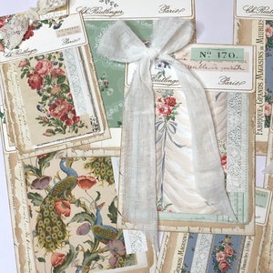 May include: A collection of vintage fabric samples with floral and peacock designs. The samples are arranged on a white surface with a white ribbon and lace accents. The text on the samples includes "Ch. Reutlinger", "Paris", "N. 170", "Meuble De March&eacute;", and "Fabrique Grands Magasins De Meubles".