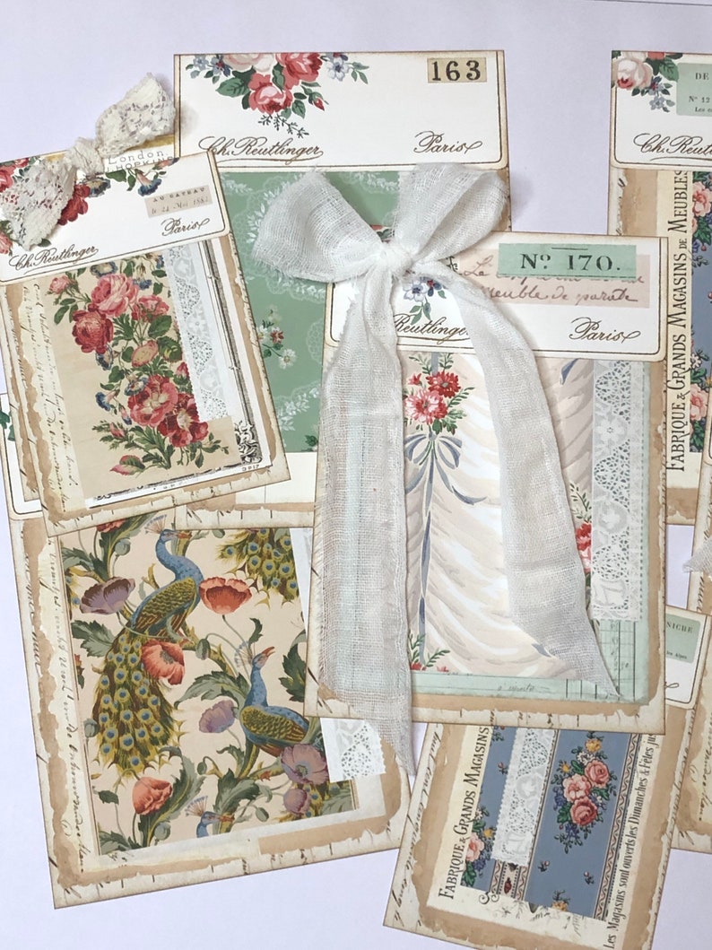 May include: A collection of vintage fabric samples with floral and peacock designs. The samples are arranged on a white surface with a white ribbon and lace accents. The text on the samples includes "Ch. Reutlinger", "Paris", "N. 170", "Meuble De March&eacute;", and "Fabrique Grands Magasins De Meubles".