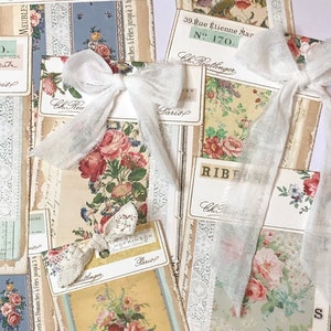 May include: A collection of vintage Parisian shop labels and ephemera with floral patterns and lace trim. The labels feature the text "Ch. Reutlinger" and "Paris".