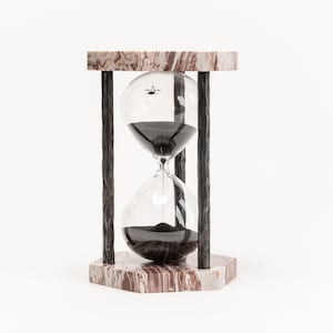 May include: A black sand hourglass with a marble base and black metal frame. The hourglass is on a white background.