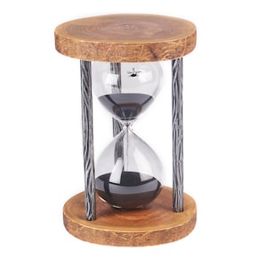 Puede incluir: Un reloj de arena de madera con un temporizador de arena negra y un marco de metal. El reloj de arena está sobre una base de madera con veta de madera natural.