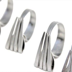 May include: Four silver napkin rings, each shaped like a fork with multiple tines.