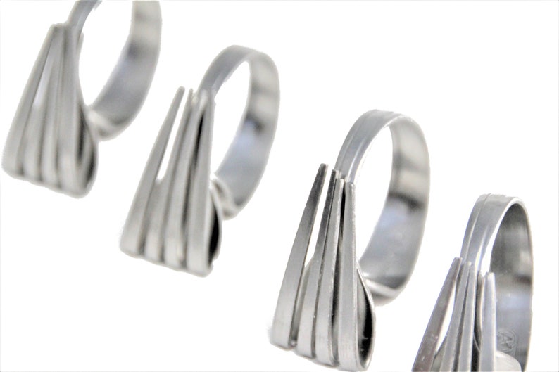 May include: Four silver napkin rings, each shaped like a fork with multiple tines.