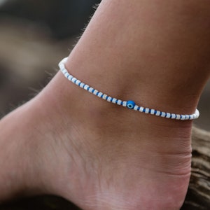 May include: White and blue beaded anklet with a blue evil eye charm.