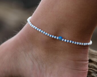 May include: White and blue beaded anklet with a blue evil eye charm.