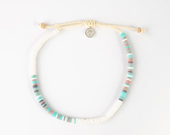 May include: A white beaded bracelet with a turquoise, brown, and gray color scheme. The bracelet has a palm tree charm.