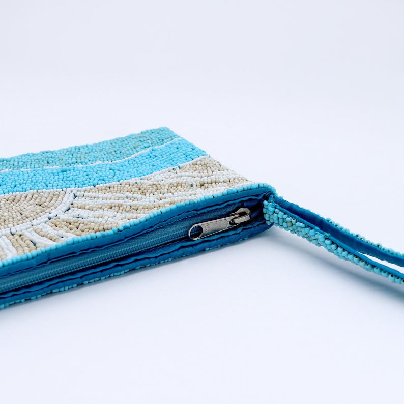 May include: A beaded clutch in shades of blue and cream, with a zipper closure and a matching beaded wrist strap. The clutch features a striped pattern with a fan-like design in the center.