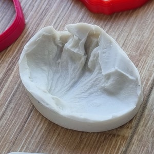 May include: A white silicone mold for making a flower, with a detailed texture on the inside.