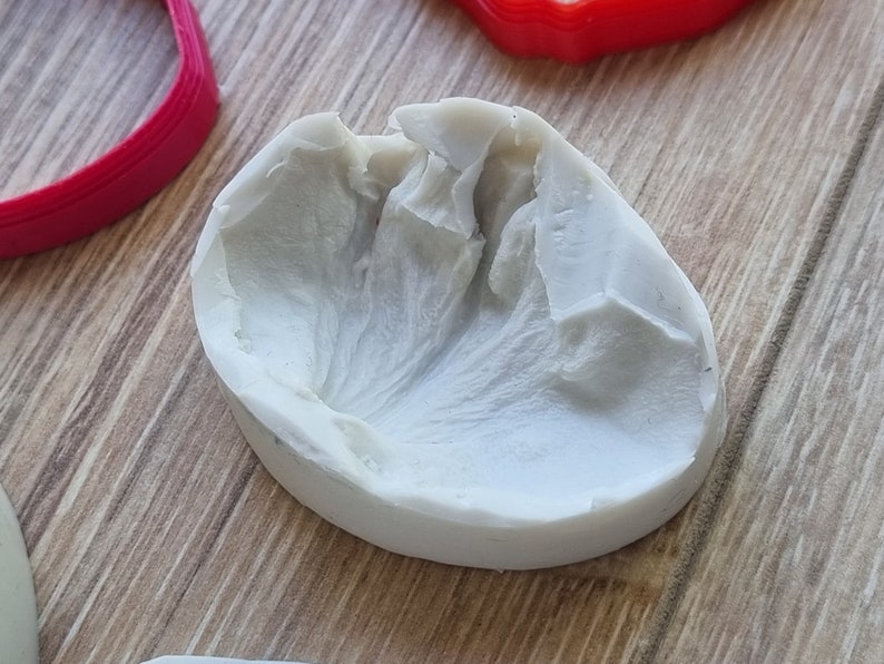 May include: A white silicone mold for making a flower, with a detailed texture on the inside.