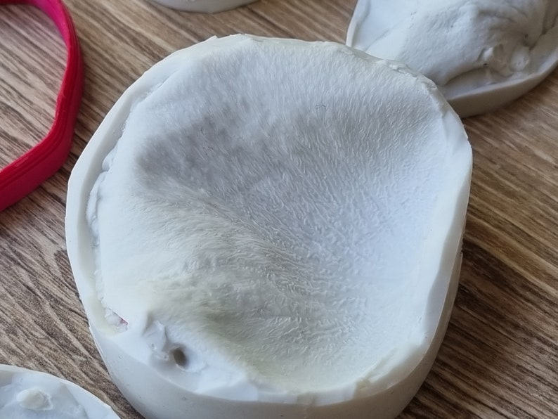 May include: A white silicone mold with a textured surface, resembling a flower bud.
