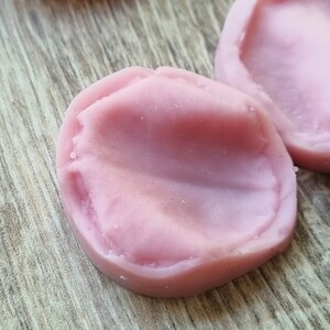 以下が含まれることがあります： 樹脂工芸品を作るためのピンクのシリコンモールド2個。モールドは丸型で、滑らかでわずかにテクスチャのある表面をしています。