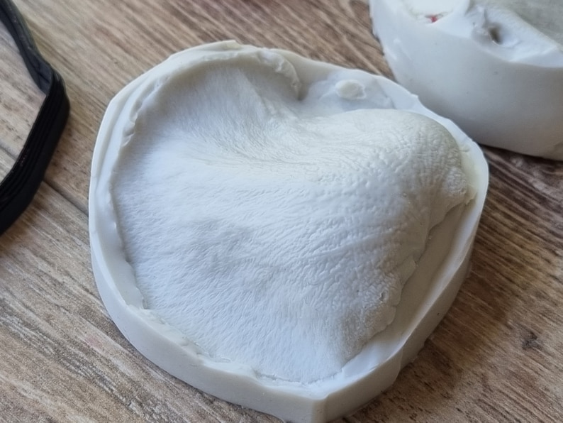 May include: A white silicone mold with a textured surface, resembling a furry animal paw print.