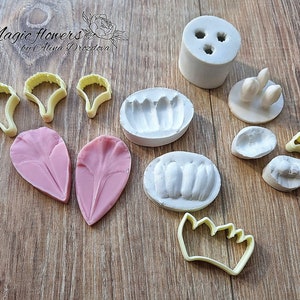 Könnte beinhalten: Ein Set aus Silikonformen und Ausstechern zum Herstellen von Polymer Clay Blumen. Das Set enthält Formen für Blütenblätter, Blätter und ein Mittelstück. Es gibt auch Ausstecher zum Formen der Blütenblätter und Blätter. Die Formen und Ausstecher sind gelb und rosa.