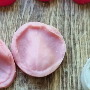 以下が含まれることがあります： 樹脂工芸品を作るためのピンクのシリコンモールド2個。モールドは丸型で、わずかに盛り上がった縁があります。