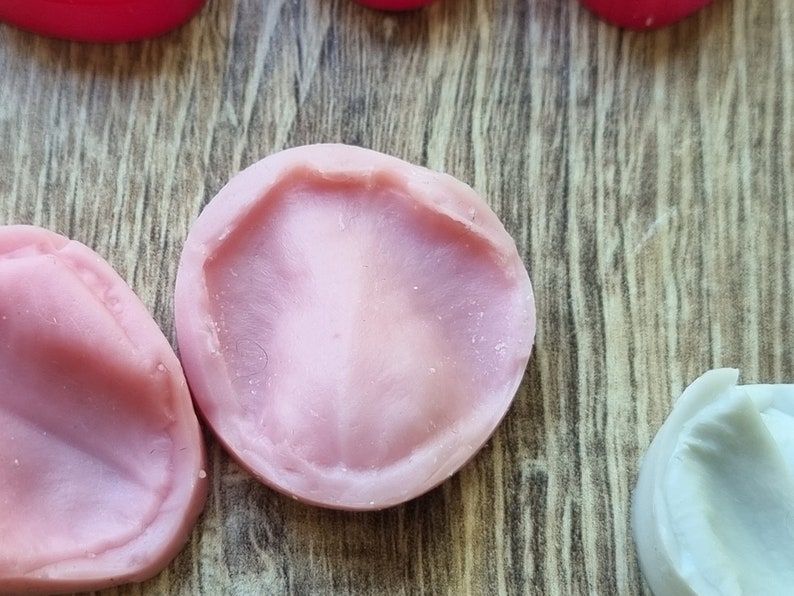 以下が含まれることがあります： 樹脂工芸品を作るためのピンクのシリコンモールド2個。モールドは丸型で、わずかに盛り上がった縁があります。
