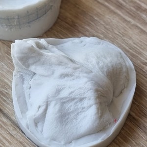 May include: A white silicone mold with a detailed design of a mountain range. The mold is sitting on a wooden surface.
