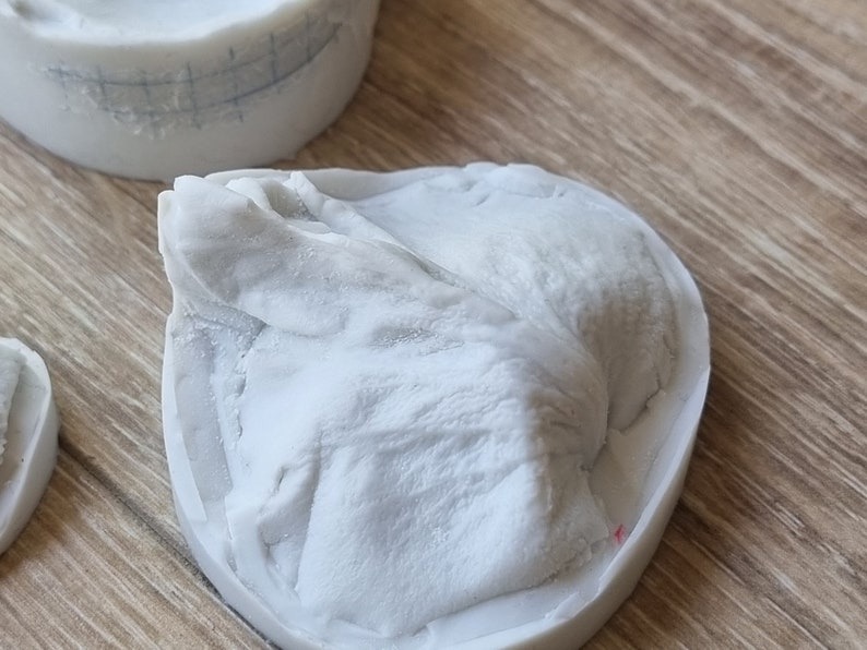 May include: A white silicone mold with a detailed design of a mountain range. The mold is sitting on a wooden surface.
