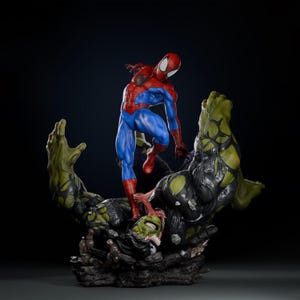 May include: A detailed statue featuring Spider-Man in a dynamic pose, clad in his iconic red and blue suit, standing over a green and black figure. The statue has a dark background, highlighting the vibrant colors of the characters.