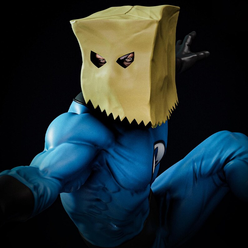 May include: A superhero figure in a dynamic pose, wearing a blue bodysuit and black gloves. The character's face is concealed by a tan paper bag mask with eye cutouts. The background is dark.
