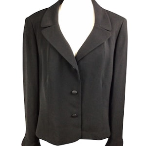 May include: A black blazer with a notched lapel and two-button closure. The long-sleeved jacket is displayed on a white mannequin, showcasing its tailored fit and classic design. The blazer's fabric appears smooth and solid.