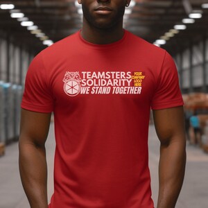May include: Red t-shirt with white text that reads "Teamsters Solidarity We Stand Together" and a white logo with a circle and two horses. The text "Your Company Logo Here" is also on the shirt.