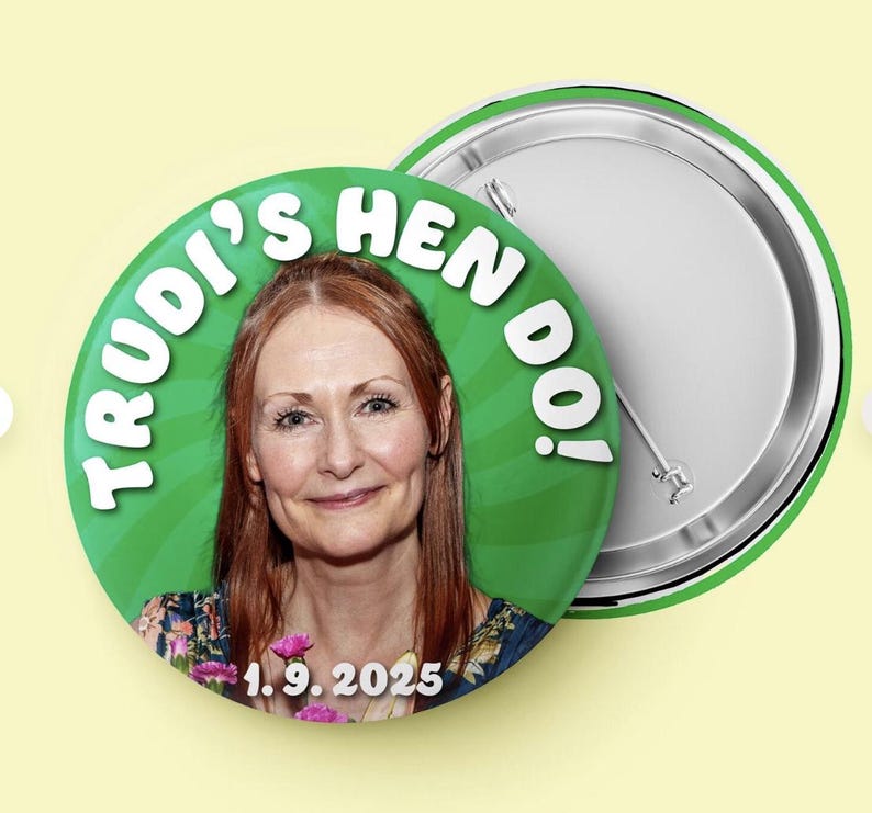 May include: A circular pin-back button featuring a photograph of a person with reddish-brown hair. The background is green with a radial pattern. The text reads "TRUDI'S HEN DO!" in white letters at the top and "1.9.2025" in white at the bottom.