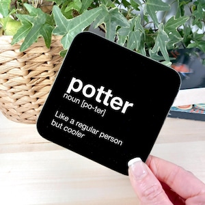 May include: Black square coaster with white text that reads "potter noun [po-ter] Like a regular person but cooler"