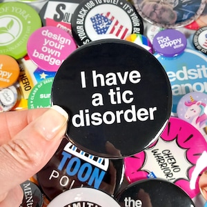 May include: A collection of colorful button pins with various designs, including a black button with white text that reads "I have a tic disorder".