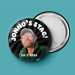 May include: A circular pin-back button featuring a photograph of a person with a beard wearing glasses and a green fleece jacket. The background is a black and white spiral pattern with the white text JONNO'S STAG! and the date 25. 7. 2025.