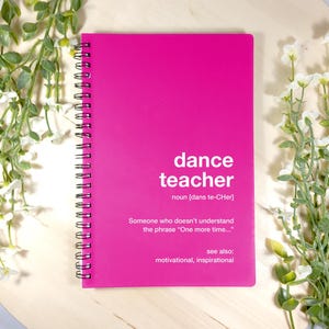 Può includere: Un quaderno a spirale rosa con le parole "dance teacher" in bianco. Il quaderno contiene una definizione della parola "dance teacher" e dice "Qualcuno che non capisce la frase "Ancora una volta..." vedi anche: motivazionale, ispiratore."
